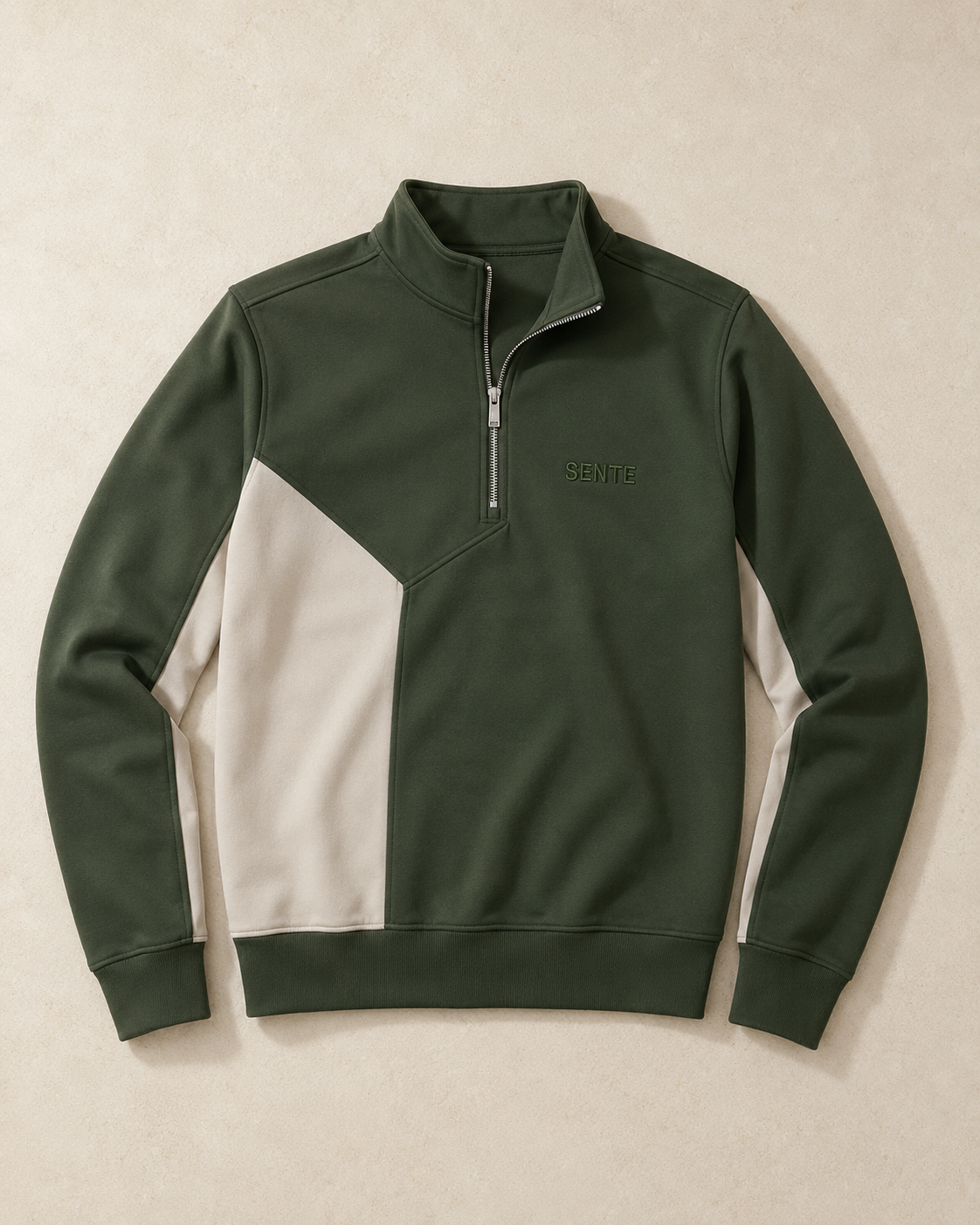 A dark green and off-white color-blocked quarter-zip sweatshirt with a stand collar, laid flat against a textured beige background. The brand name 'SENtE' is subtly embroidered on the left chest.