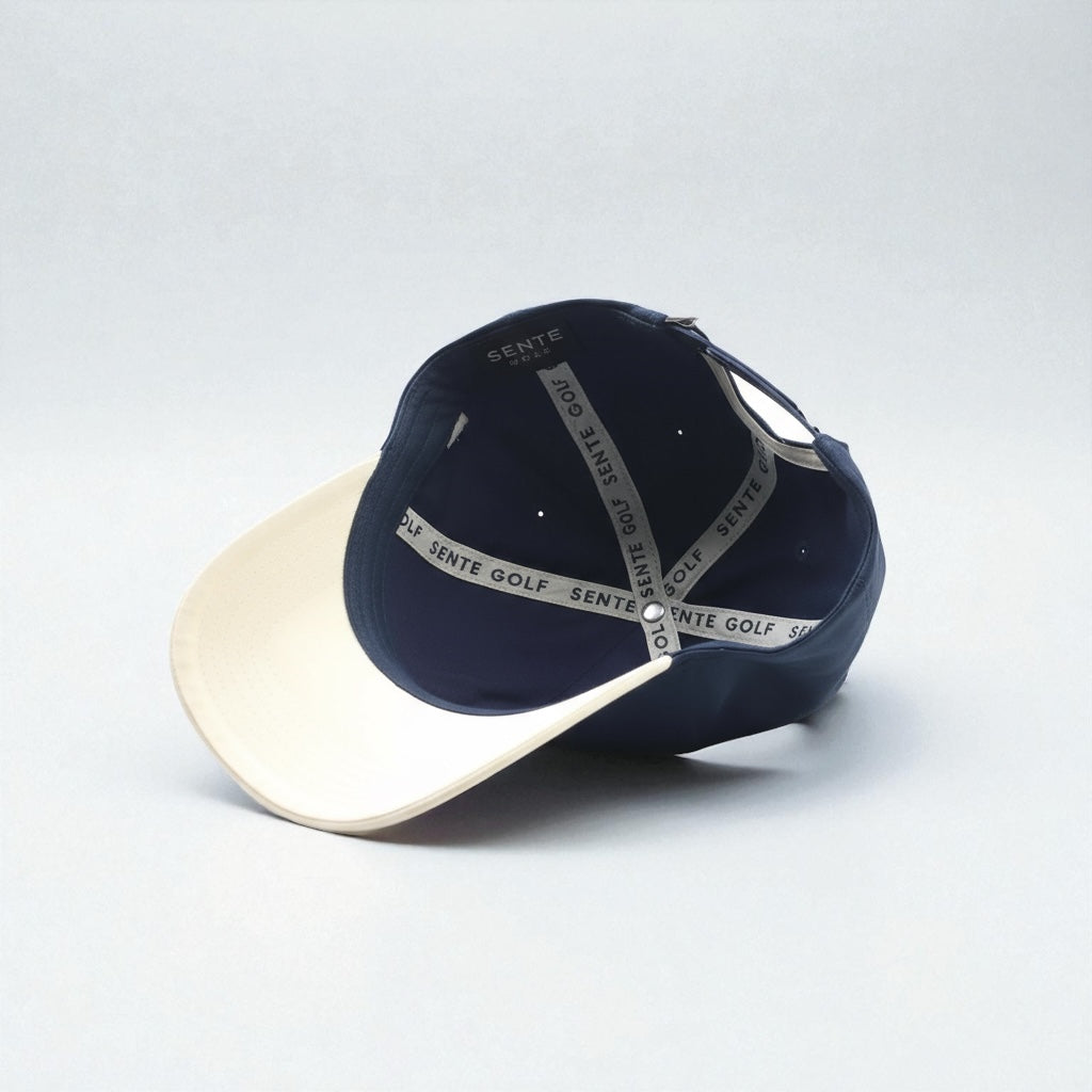 Navy and beige cap with branding on a light gray background