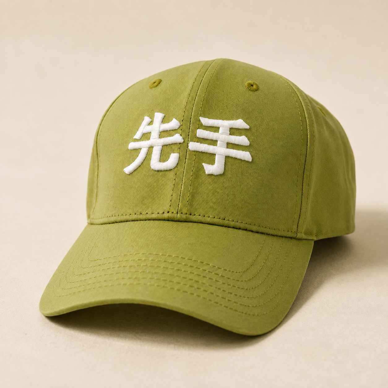 An olive green baseball cap with white embroidered Japanese kanji characters on the front, displayed on a neutral beige background.