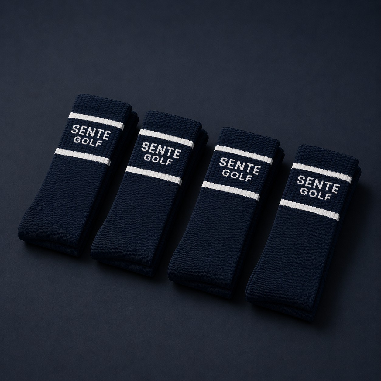 Four pairs of navy blue socks with 'Sente Golf' branding on a dark background