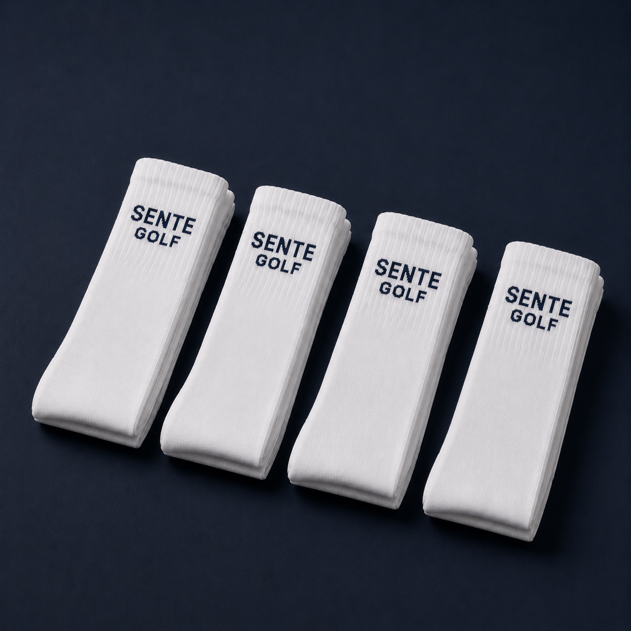 Four white socks with 'SENTE GOLF' branding on a dark background